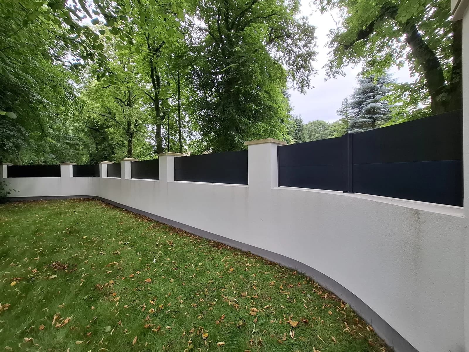 Anthracite aluminium fence panels between rendered pillars on a curved garden wall