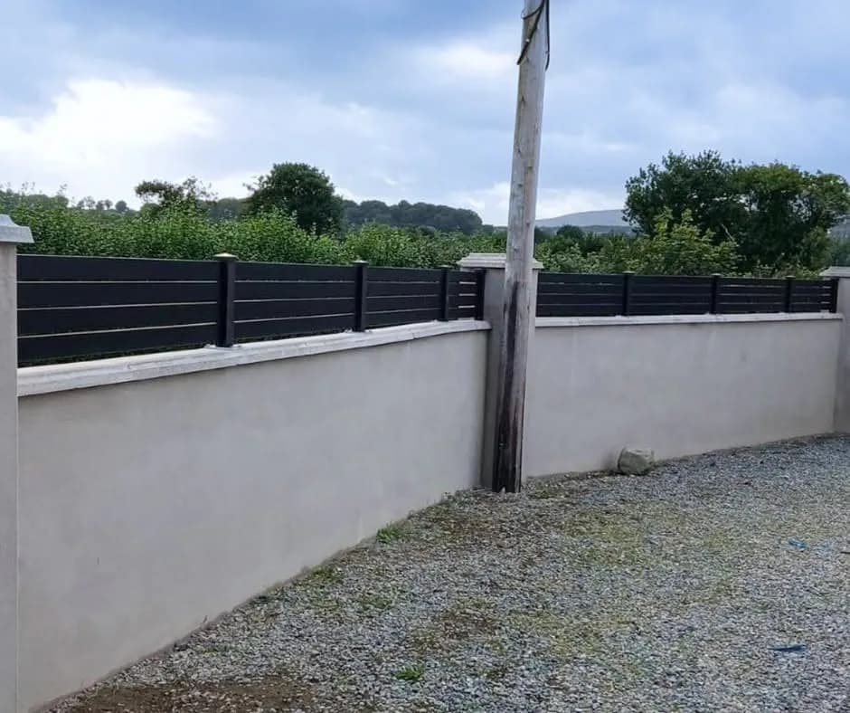 Anthracite slatted aluminium fence on top of a rendered garden wall