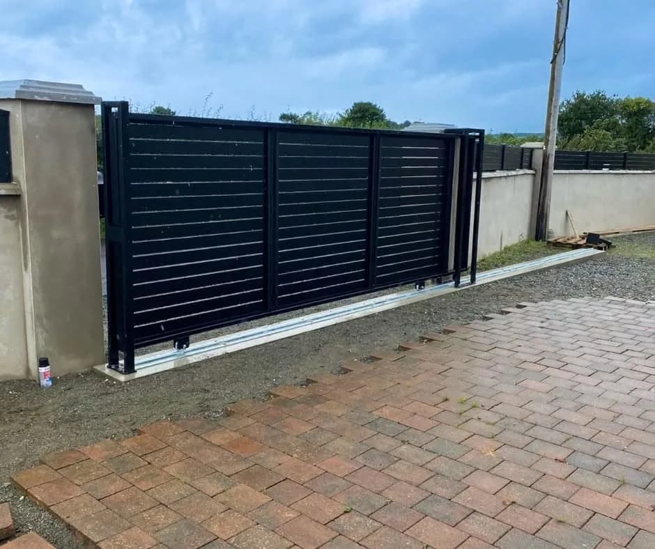 Anthracite slatted aluminium sliding gate across a block-paved driveway